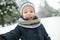 Cute toddler boy having fun on a walk in snow covered pine forest on chilly winter day. Child exploring nature