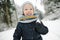 Cute toddler boy having fun on a walk in snow covered pine forest on chilly winter day. Child exploring nature