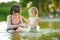 Cute toddler boy and his big teenage sister playing by a river on hot summer day. Adorable child having fun outdoors during summer