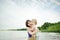 Cute toddler boy and his big teenage sister playing by a river on hot summer day. Adorable child having fun outdoors during summer