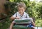 Cute toddler boy sits in front of a large stack of children`s books, reads intently