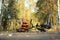 Cute toddler boy sitting on empty road in autumn park his eyes closed, child`s bicycle lies nearby. Fall vibes