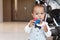 Cute toddler boy in suit with bowtie showing toy care