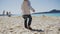 Cute toddler boy in sun protective hat walks on wet sand