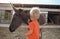 Cute toddler boy touching and stroking baby donkey on farm in Cyprus