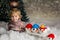 Cute toddler child, holding knitted toy, playing in the snow with colorful snowmen