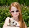 A cute toddler girl with colored sunglasses on holding her little dog