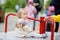 Cute toddler girl having fun on outdoor playground. Baby rides on carousel. Kindergarten, daycare for small children. Equipment