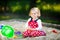 Cute toddler girl playing in sand on outdoor playground. Beautiful baby in red gum trousers having fun on sunny warm