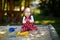 Cute toddler girl playing in sand on outdoor playground. Beautiful baby in red gum trousers having fun on sunny warm