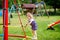 Cute toddler girl playing on slide on outdoor playground. Beautiful baby in colorful shorts trousers having fun on sunny