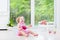 Cute toddler girl playing tambourine in white room