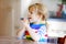 Cute toddler girl praying to God at home. Child using hands for pray and thank for food. Christian tradition.