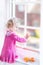 Cute toddler girl watching out of a window