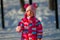 Cute toddler girl wearing bright colored overall playing with snow