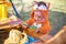 Cute toddler in orange jumpsuit plays in the sand in sandbox outdoors on a sunny day