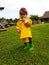 Cute toddler standing finger in mouth in front of Collection of firewoods in piles