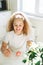 Cute tween girl with long curly hair painting eggs on kitchen at home on the spring sunny day, Happy Easter