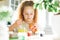 Cute tween girl with long curly hair painting eggs on kitchen at home on spring sunny day, Happy Easter