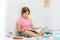 Cute tween girl in pink t-shirt reading book sitting on bed in bright room at the home