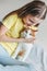 Cute tween girl in yellow t-shirt with her white cat at home