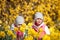 Cute twin sisters, embrace on a background field with yellow flowers, happy cute and beautiful sisters having fun with yellow flow