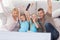 Cute twins and parents raising arms while watching television