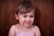 Cute upset little girl on dark wooden background