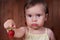 Cute upset little girl is holding the big ripe strawberry