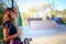 Cute urban girl with skateboard drinking water on a hot day