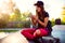 Cute urban girl in skatepark with skateboard using smart phone