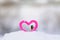 Cute Valentine card with bird tit Peeps out of the frame knitted decorative element pink heart stands in the snow in the Park