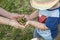 Cute view of female hands holding child`s hands with green pine cones.