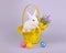 Cute white bunny in a basket with flowers and Easter eggs