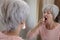 A cute white haired senior woman is using a mouth spray