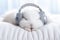 Cute white rabbit listening to music with headphones on bed at home. selective focus. Generative AI