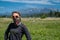 Cute, wholesome adult woman with braided hear poses in a meadow in Polebridge Montana. Neck gaiter face mask during COVID-19