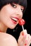 Cute woman with bright make up, red lips and colorfull eyeshadows. Smiling girl eat red candy. Pretty woman with white teeth