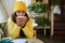 Cute woman in bright yellow clothes, taking a sip of hot coffee while resting in a cozy coffee house with rustic design