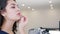 Cute woman doing make-up in front of mirror indoors on unfocused background