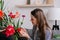 Cute woman enjoys smell of fresh flowers in living room. Happy adult housewife lady doing household activity pouring flowers