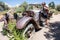 Cute woman hiker poses by an abandoned old fashioned car rusting and decaying in the desert of Joshua Tree National Park