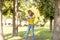 Cute woman is reading pleasant text message on mobile phone while taking a walk in the park in warm fall day