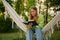 Cute woman relaxing in hanging hammock and reading the book