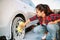 Cute woman scrubbing vehicle wheel with foam