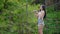 Cute woman stands on bridge over river and takes photos with film camera