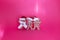 Cute wooden cat figurine trio in Christmas outfits on hot pink background