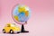 Cute yellow little retro car with world globe sphere. Travel concept. Planning summer vacations