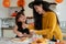 A cute young Asian girl is enjoying making Halloween desserts with her mom in the kitchen