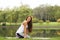 Cute young beautiful girl sitting in yoga pose on the riverside have a rest after workout. Health and sport concept